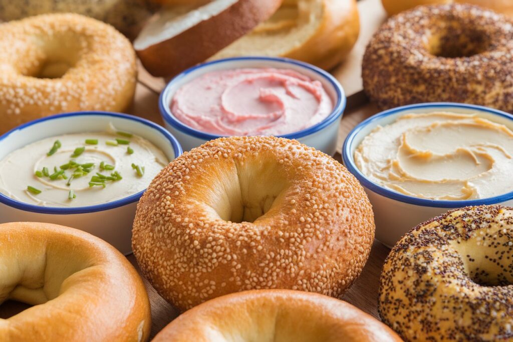 Assorted bagels and cream cheese varieties displayed on a table.